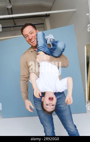 Glücklicher Vater, der seinen Sohn in der umgekehrten Position hält Stockfoto
