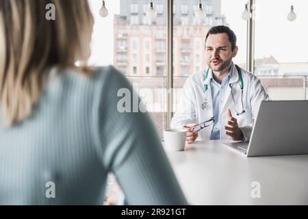 Arztberatender Patient am Tisch in der Klinik Stockfoto