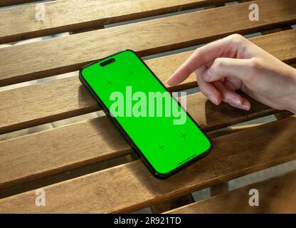 Lodz, Polen, 19 2023. Juni Hand mit Handy-Bildschirmmodell auf Holztisch. Stockfoto