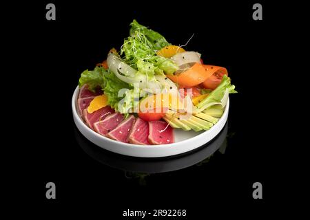 Seltene gebratene Thunfischscheiben mit frischem Gemüsesalat auf einem Teller. Stockfoto