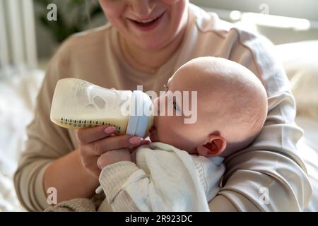 Mutter füttert das kleine Mädchen zu Hause mit Milch Stockfoto