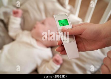 Mutter prüft die Temperatur des Mädchens durch Thermometer zu Hause Stockfoto