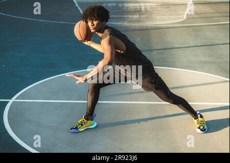 Sportler, der Basketball im Stehen auf dem Sportplatz wirft Stockfoto