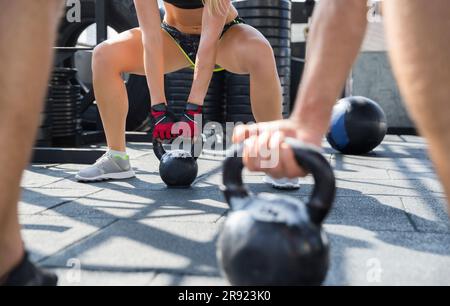 Freunde, die im Fitnessstudio auf dem Dach mit Kugelhanteln trainieren Stockfoto