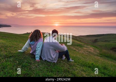 Freunde, die auf dem Rasen den Sonnenuntergang beobachten Stockfoto