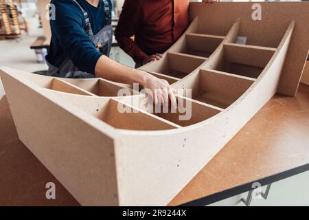 Geschäftsmann mit Zimmermann, der Holz in der Werkstatt untersucht Stockfoto