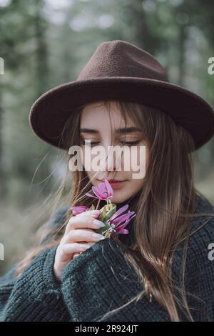 Schöne junge Frau mit langen Haaren, die nach Blumen riecht Stockfoto