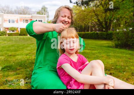 Glückliche Mutter kämmt die Haare der Tochter Stockfoto