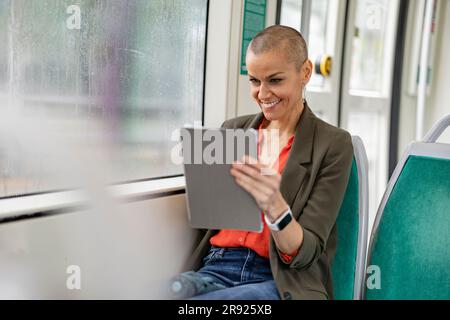 Frau mit Tablet-PC, die in der Straßenbahn sitzt Stockfoto