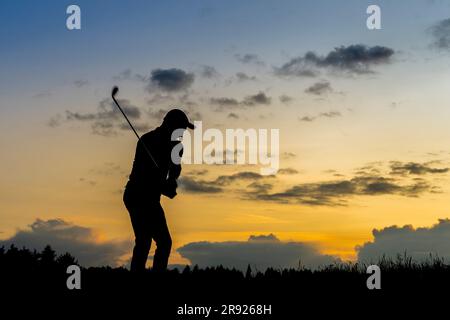 Silhouette eines Mannes, der in der Dämmerung Golf spielt Stockfoto