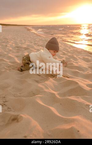 Süßer kleiner Junge, der am Strand im Sand spielt Stockfoto