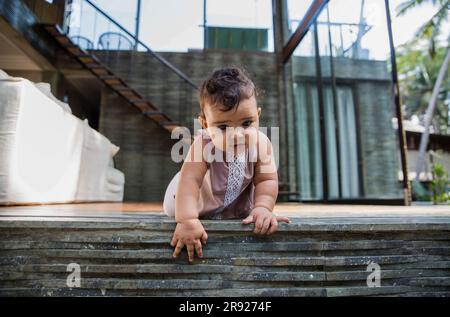 Ein kleines Mädchen, das zu Hause auf dem Boden krabbelt Stockfoto