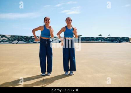 Zwillingsschwestern tanzen zusammen an sonnigen Tagen Stockfoto