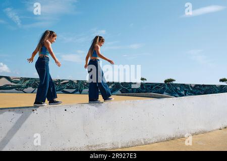 Mädchen, die im Skateboard-Park an der Wand spazieren Stockfoto