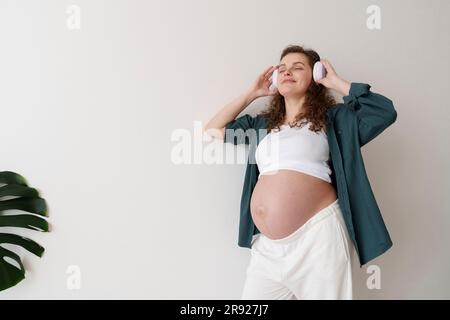 Lächelnde schwangere Frau anhören von Musik Stockfoto
