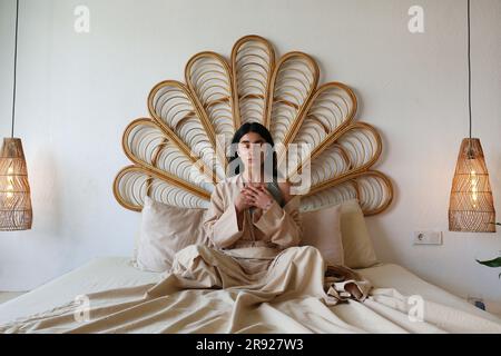 Junge Frau, die zu Hause im Bett meditiert Stockfoto