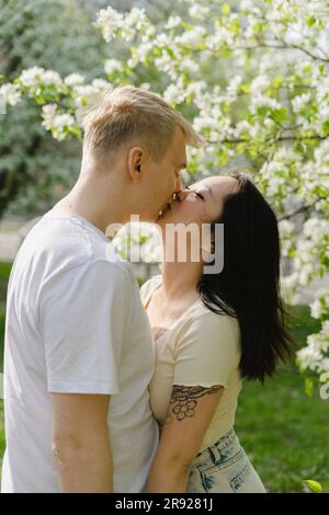 Ein junges Paar küsst sich am blühenden Baum im Park Stockfoto