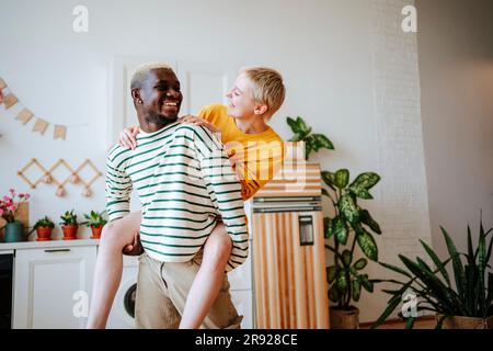 Glücklicher junger Mann, schweinende Freundin in der Küche Stockfoto