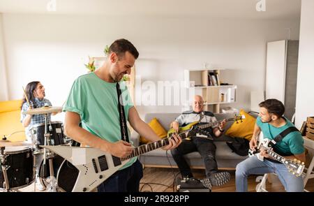 Rockmusiker üben zu Hause mit Musikinstrumenten Stockfoto