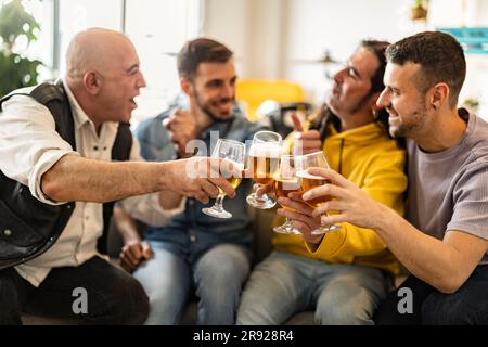 Glückliche Freunde, die zu Hause Bier toasten Stockfoto