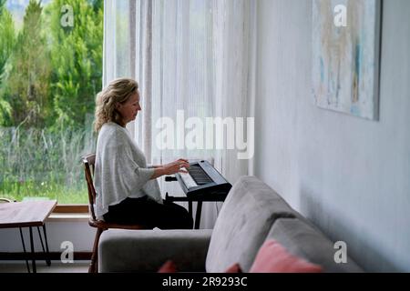 Seniorin spielt zu Hause Klavier Stockfoto