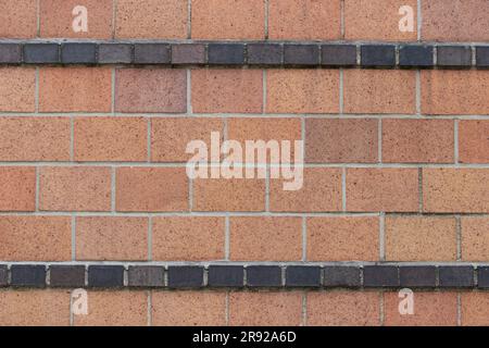Breite Terracotta-Ziegel in Trage oder Laufband mit Streifen aus schwarzen Halbziegeln, kunstvoll dekorative Backsteinwand im Art déco-Stil Stockfoto