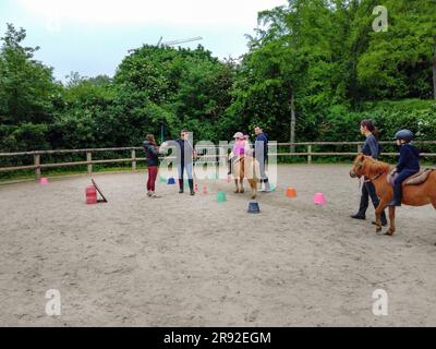 05-14-2023 Paris, Frankreich. Kinder reiten Ponys (Pferde) und schießen Pfeile auf die Eltern neben ihnen auf der Insel Saint-Germain (Paris) Stockfoto