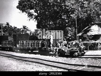 Ein an Schienen angepasster Jeep transportiert während der Schlacht um die Philippinen im Zweiten Weltkrieg einen mit Benzin beladenen Güterzug mit drei Güterwaggons in ein Kampfgebiet auf Luzon Island Stockfoto