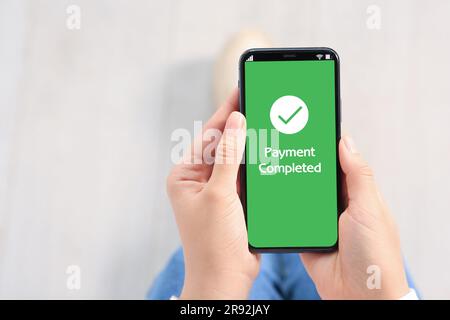 Frau hat erfolgreich mit einer Online-Banking-Anwendung auf einem Smartphone in Innenräumen bezahlt, Nahaufnahme Stockfoto