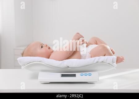 Niedliches kleines Baby, das in der Klinik auf einer Waage liegt Stockfoto