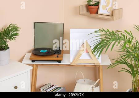 Stilvoller Plattenspieler mit Schallplatte auf Holztisch in gemütlichem Zimmer Stockfoto