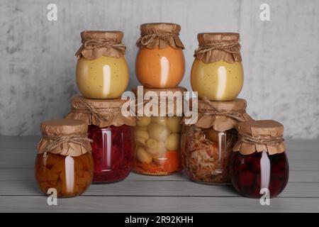 Viele Glasgefäße mit verschiedenen konservierten Produkten auf einem Holztisch Stockfoto