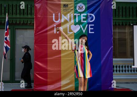 Bangkok, Thailand. 23. Juni 2023. BANGKOK, THAILAND. JUNI 23 - jemand posiert für ein Foto vor einem Regenbogenbanner für das Ereignis „United in Love“ im Haus in Sathorn in Bangkok am 23. Juni 2023. Die britische Botschaft Bangkok und die USA Embassy Bangkok veranstaltet im W Hotel ein jährliches LGBTQIA Pride Event, um die Bemühungen von Menschenrechtsverteidigern zu würdigen, die sich für LGBT-Rechte und -Inklusion einsetzen, und um das Engagement Großbritanniens und der USA für Gleichberechtigung, Gleichstellung und LGBT-Gemeinschaften in Thailand zu bekräftigen. Kredit: Matt Hunt/Neato/Alamy Live News Stockfoto