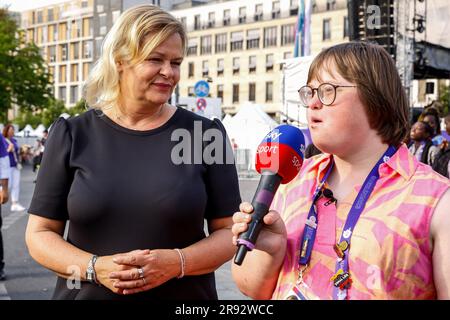 Die Freiwilligenjournalistin mit Down-Syndrom interviewt die deutsche Innenministerin Nancy Faeser für Sky Sport während der Straßenparty für Sportler und Fans der Special Olympics. Sommerspiele Berlin 2023 vor dem Brandenburger Tor im Zentrum Berlins. Die Berliner Spiele 2023 sind Gastgeber von 7000 Lernbehinderten aus fast 190 Ländern. Special Olympics ist eine internationale Wohltätigkeitsorganisation, deren Ziel es ist, Lernbehinderte in den Bereich des Olympischen Sports einzubeziehen. Berlin 2023 ist die größte Sport- und Wohltätigkeitsveranstaltung des Jahres 2023. Stockfoto