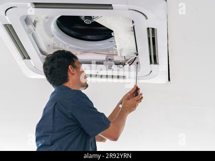 Techniker, der die Deckenklimaanlage im Büro repariert. Stockfoto