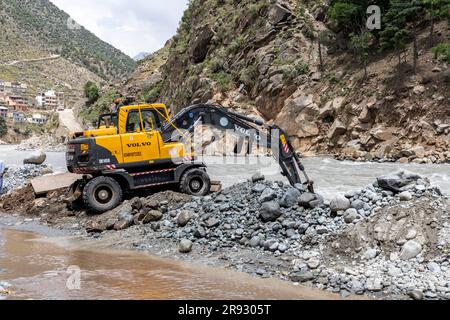 Der Bagger, der am Bau einer Barriere arbeitet, um das überschwemmte Wasser von swat-geräten zu blockieren, die in den bahrain-Basar eindringen: Bahrain swat, Pakistan - 12. Juni 2023. Stockfoto