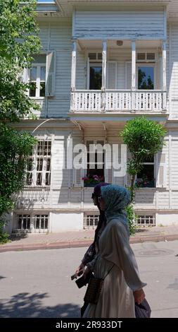 Tmuslimische Frauen spazieren vorbei an einem hölzernen Herrenhaus aus der osmanischen Ära im Besitz von Adalar auf der Insel Büyükada, Prinzessinseln, Marmarameer, in der Nähe von Istanbul, Türkei Stockfoto