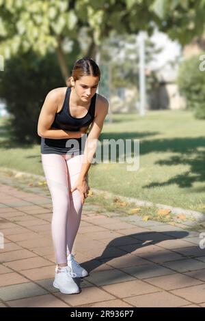 Die Sportlerin hat beim Laufen akute Schmerzen in ihrer Seite. Stockfoto