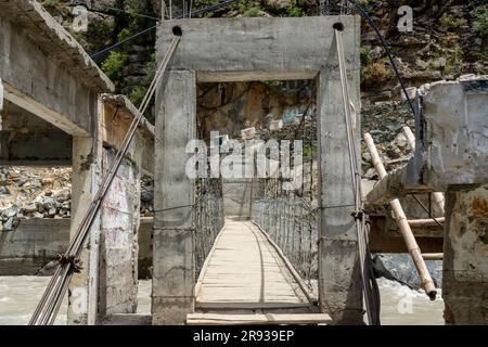 Fußgängerbrücke aus Holz und Stahlseilen über einem Fluss Stockfoto