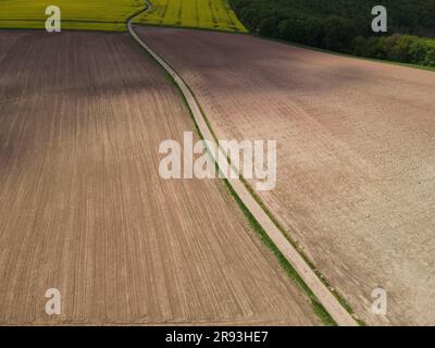 Drohnenansicht von gepflügten Ackerfeldern mit einer Spur in der Mitte Stockfoto