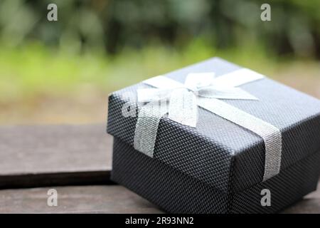Verschiedene Geschenkschachteln mit Sonnenlicht auf dem Rasen des Parks an einem sonnigen Sommertag:Schachtel für Geschenk mit goldenem Band auf dem Holztisch Stockfoto