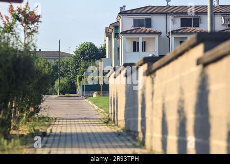 Straßenbelag umgeben von Pflanzen und einer Grenzwand von Wohnungen in einer italienischen Stadt bei Sonnenuntergang Stockfoto