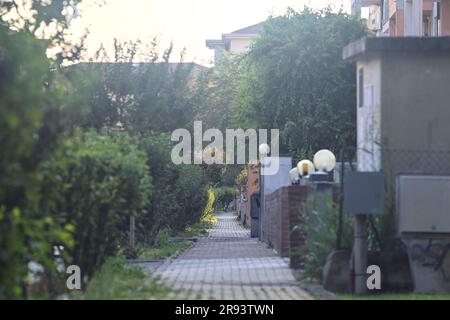 Straßenbelag umgeben von Pflanzen und einer Grenzwand von Wohnungen in einer italienischen Stadt bei Sonnenuntergang Stockfoto