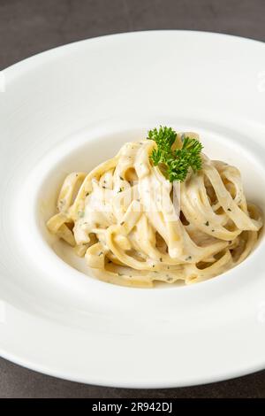 Frisch zubereiteter Fettucini alfredo auf einem weißen Porzellanteller Stockfoto