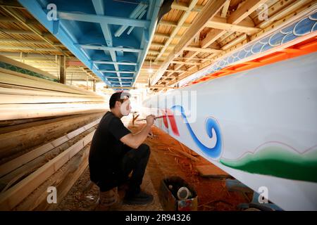 (230624) -- FUZHOU, 24. Juni 2023 (Xinhua) -- Ein Handwerker malt am 23. Mai 2023 ein Drachenboot in einer Fabrik in Minhou in der südostchinesischen Provinz Fujian. Das Dragon Boat Festival, auch bekannt als Duanwu Festival, findet traditionell am fünften Tag des fünften Monats im chinesischen Mondkalender statt. Der Drachenbootwettbewerb, ein traditioneller Teil des Festivals, hat auf beiden Seiten der Taiwan-Straße an Popularität gewonnen und eine Vielzahl von Menschen begeistert. Die Provinz Fujian liegt an der Südostküste Chinas und ist mit ihren weit verstreuten Flüssen, Seen und ideal für Wassersportarten Stockfoto