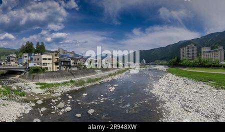 Der Fluss Hida fließt durch das Zentrum von Gero Onsen, berühmt für heiße Quellen in der Präfektur Gifu, Japan. Weitwinkelpanorama. Stockfoto