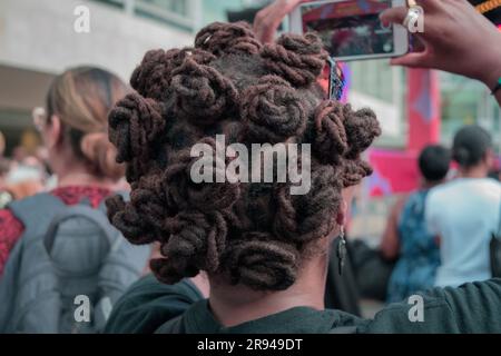 Eine schwarze Frau mit Bantu-Knoten-Haarschnitt, die auf dem Handy filmt Stockfoto