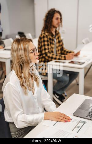 Eine attraktive blonde Frau mittleren Alters wird nach der Präsentation einen Wissenstest machen. Sie hört aufmerksam zu Stockfoto