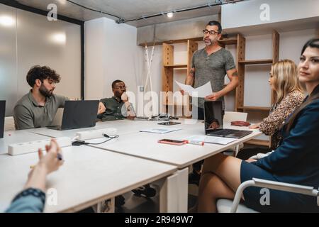 Eine Gruppe von generationenübergreifenden, multiethnischen Geschäftsleuten, die sich spät in der Nacht im Büro treffen Stockfoto