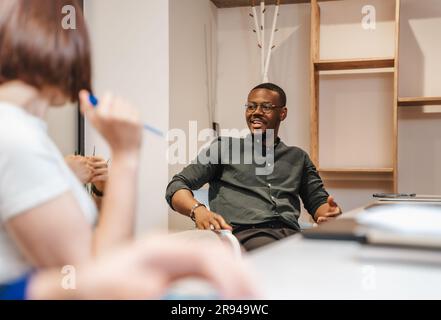 Junge, multiethnische Kollegen, die im Büro geschäftlich reden Stockfoto